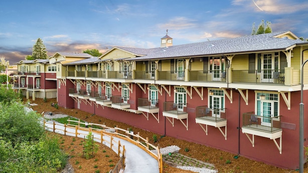 A multi-story hotel with balconies, a covered walkway, and a landscaped garden area.