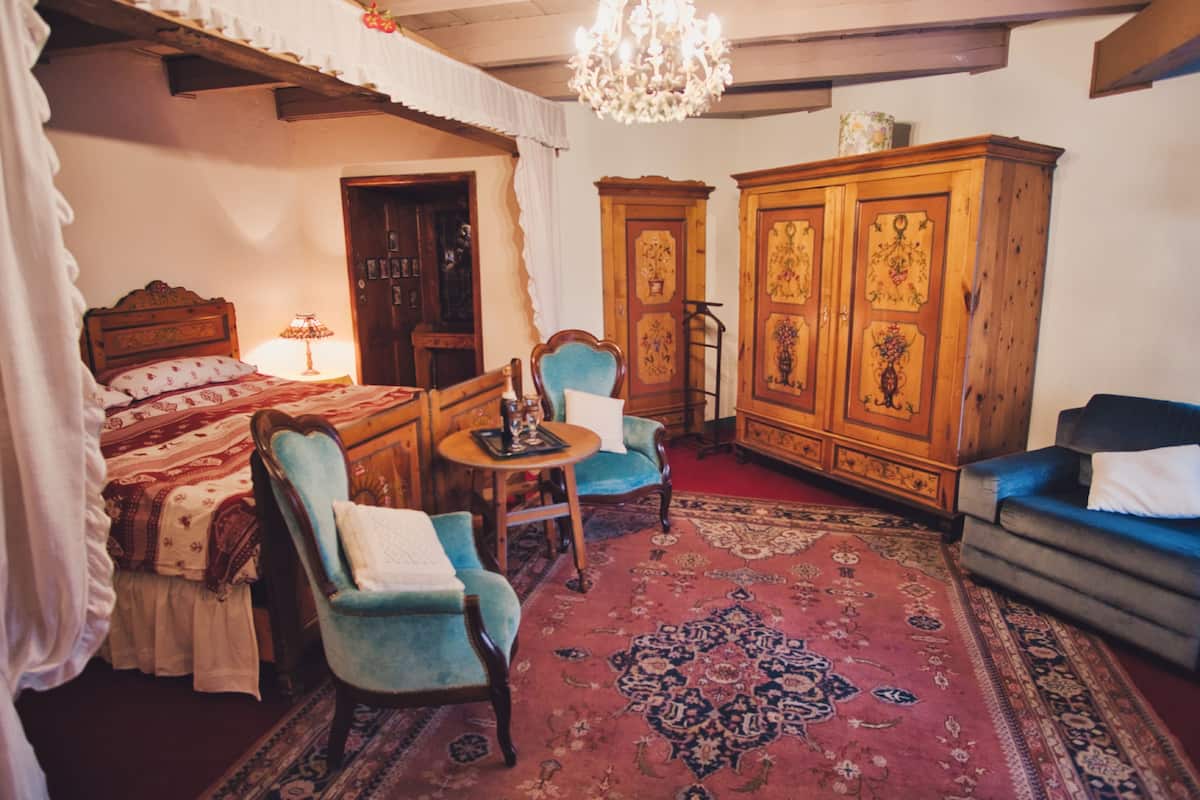 Een klassieke kamer met een bed, twee fauteuils, een bank, een houten kast en een kroonluchter.