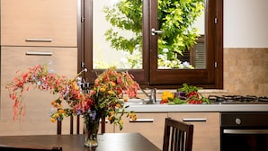 Una cocina con armarios de madera, una mesa de comedor y un florero con flores.