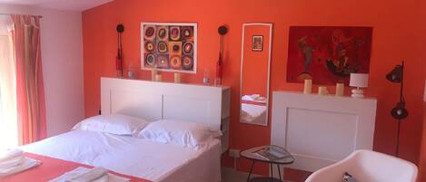 Een hotelkamer met een groot bed, een klein tafeltje, een stoel en een spiegel.