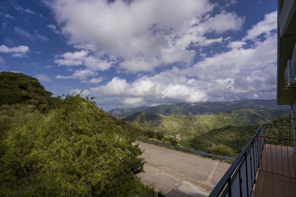A view from a balcony overlooking a mountainous landscape with a road leading down. - B&B Gàttina (Naso)