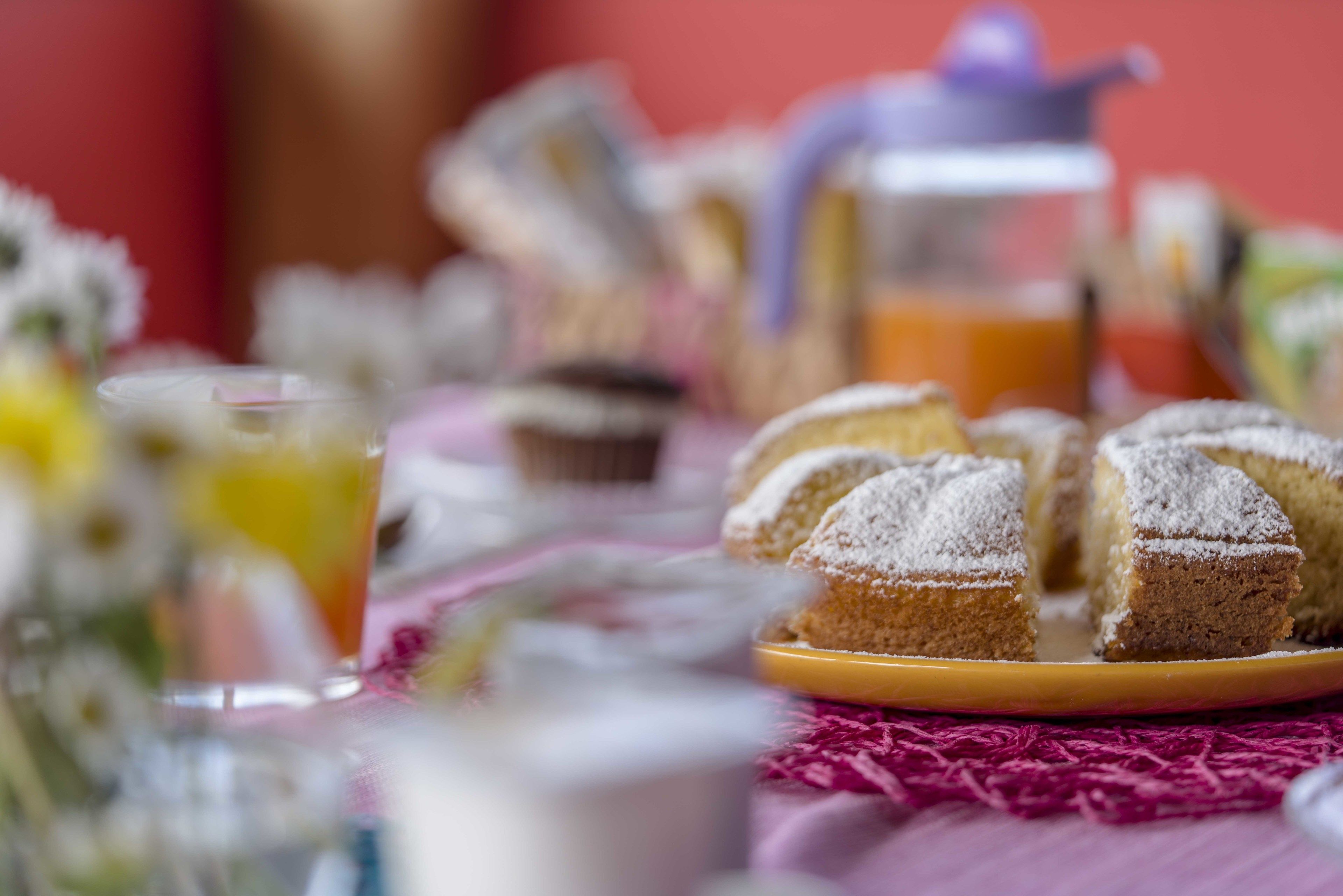 A table with a plate of pastries and a pitcher of orange juice.