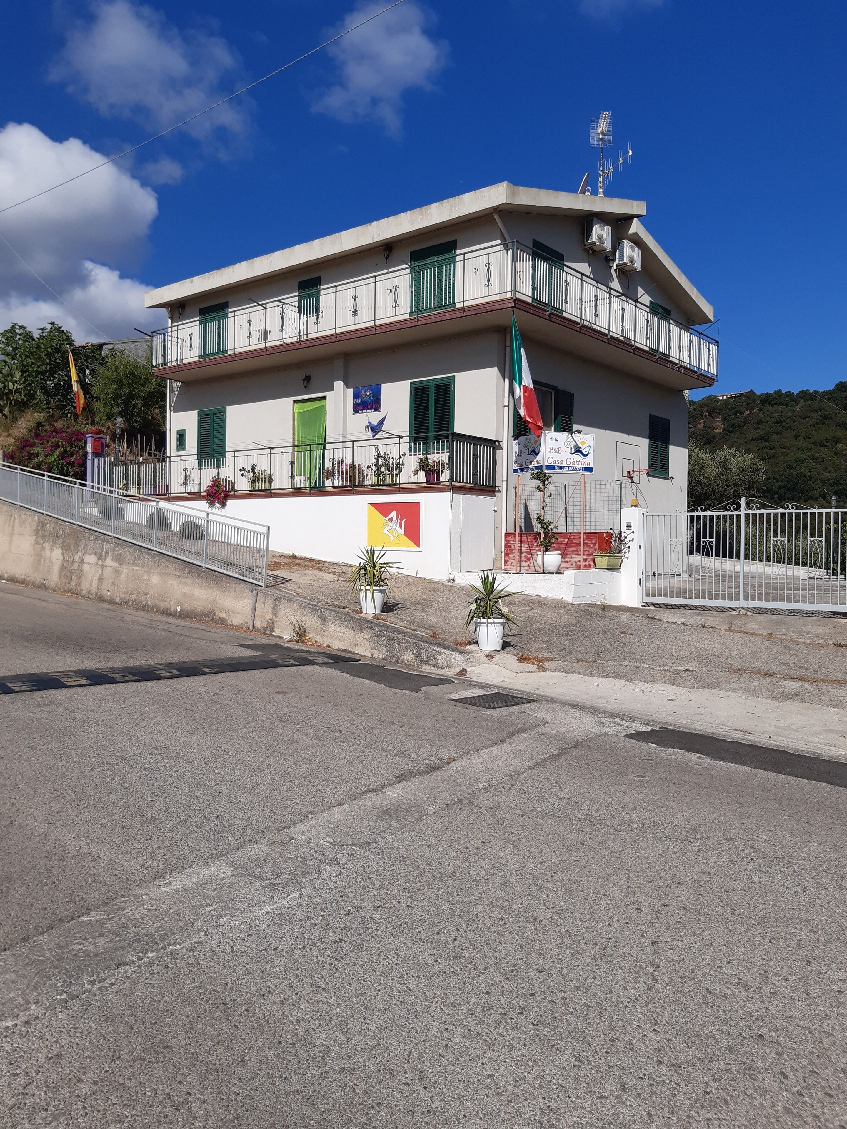 Ein zweistöckiges Gebäude mit Balkon, einer Flagge und einem Schild, das ein Bed and Breakfast anzeigt.