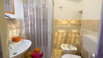 Ein Badezimmer mit Dusche, Waschbecken, Bidet und Toilette.
