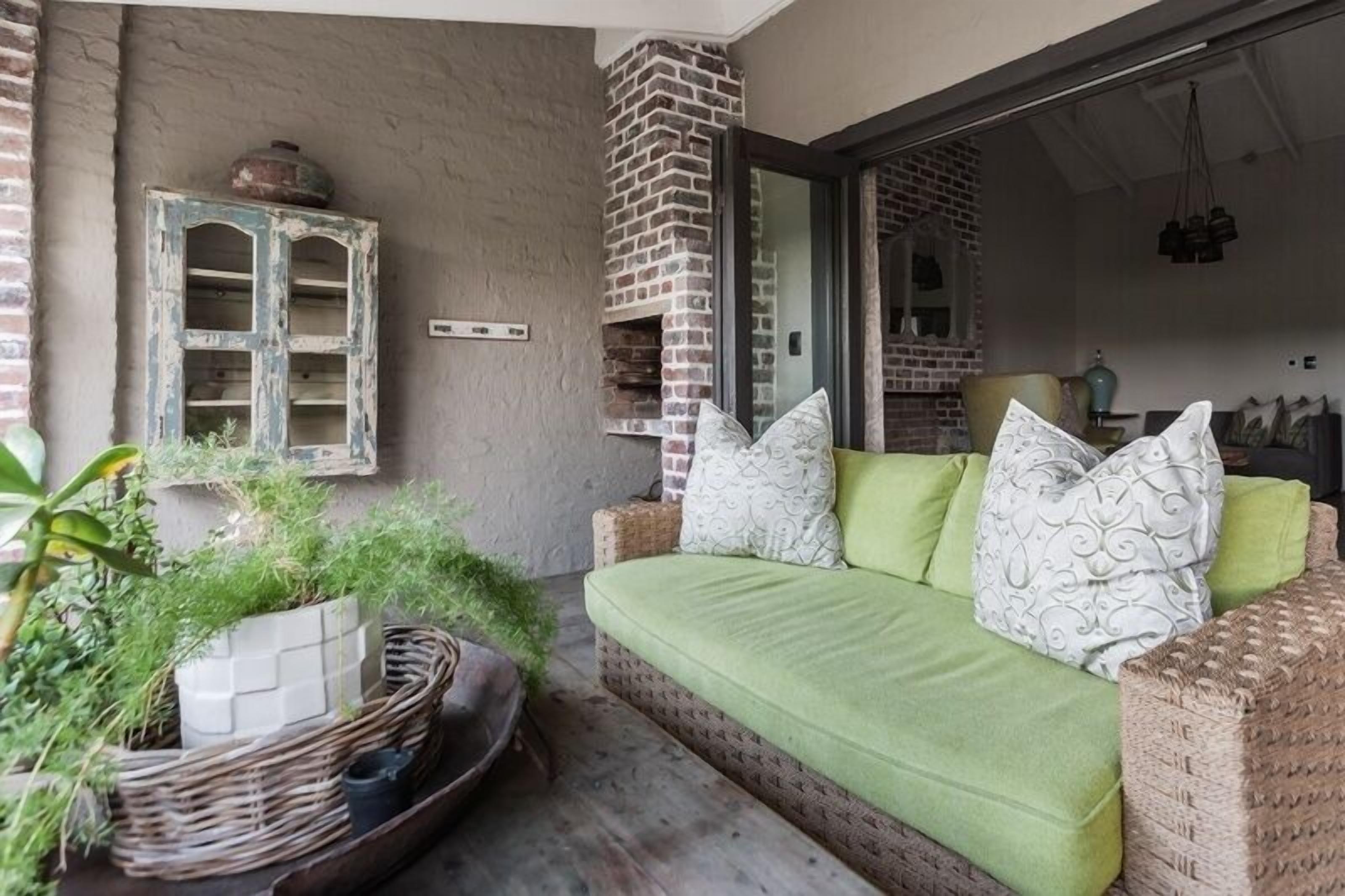 Ein gemütliches Zimmer mit einem grünen Sofa, einem Kamin aus Ziegelsteinen und einer rustikalen Wand mit einem abgenutzten Schrank.