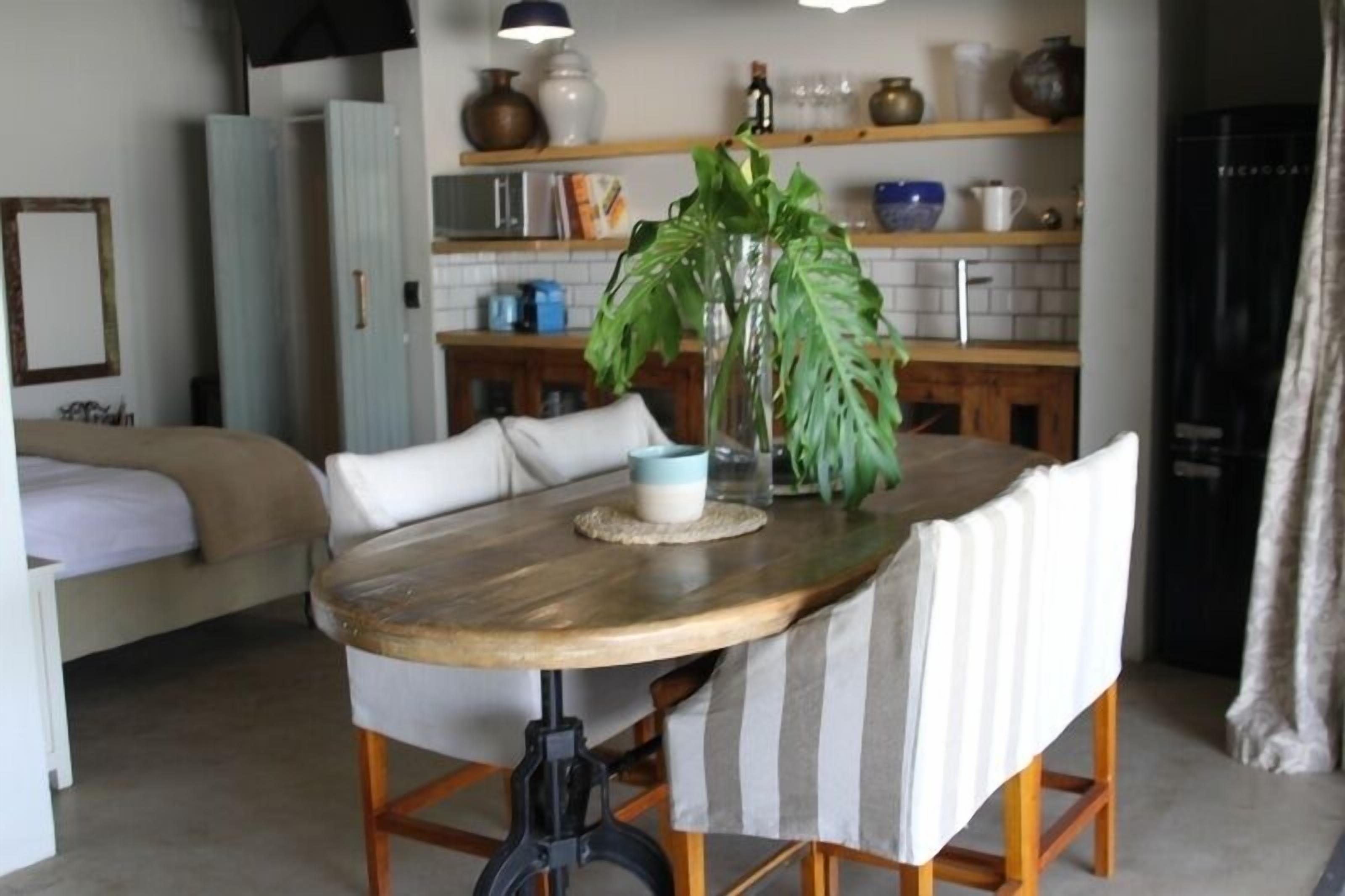 Una cocina acogedora con una mesa de madera, sillas blancas y una planta en maceta.