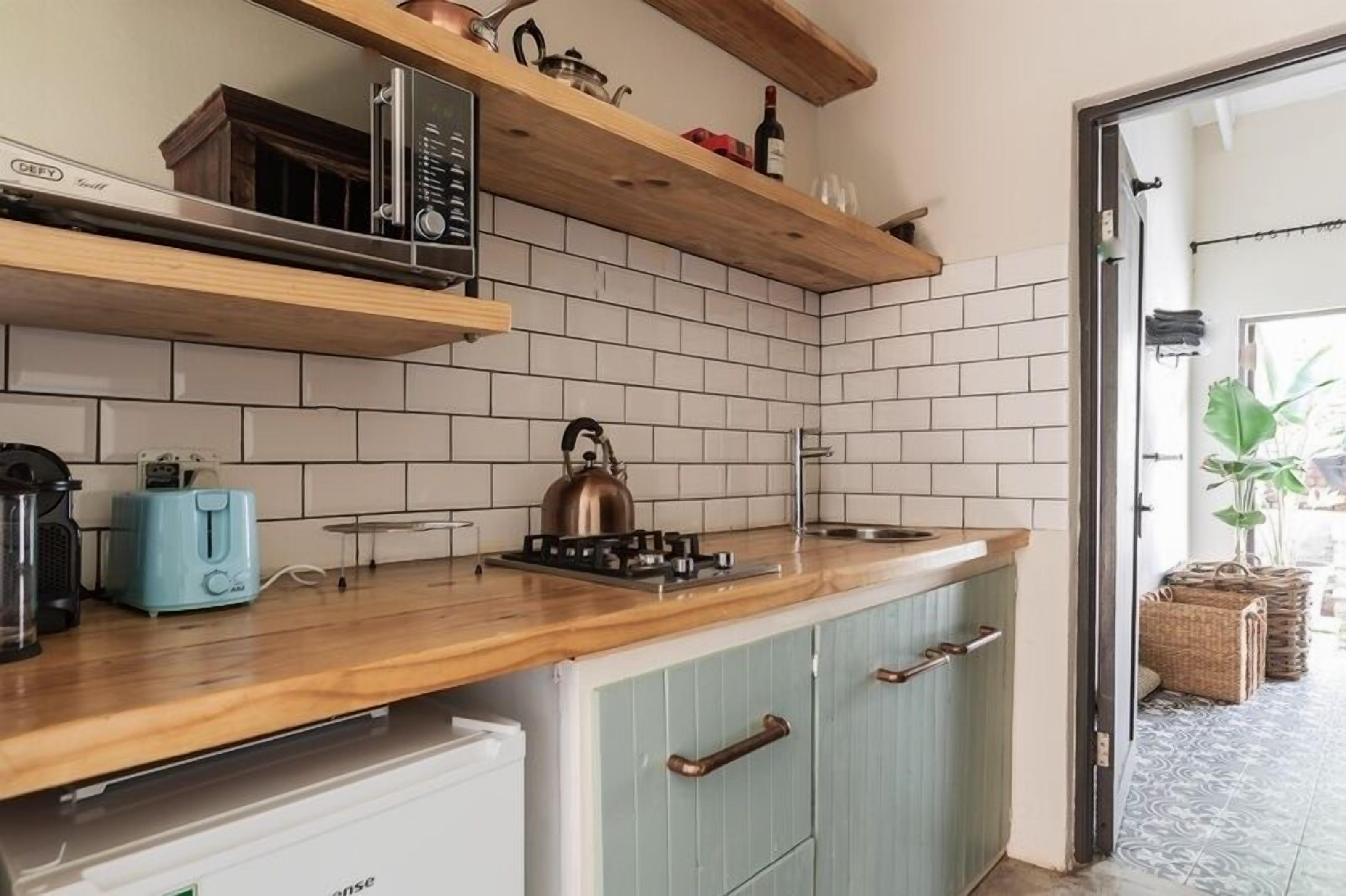 A kitchen with wooden shelves, a gas stove, a kettle, and a toaster.