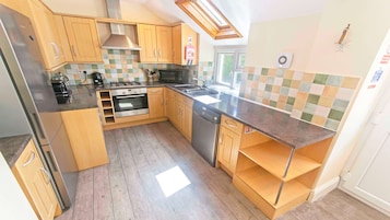 A kitchen with wooden cabinets, a stainless steel refrigerator, a gas stove, and a dishwasher.