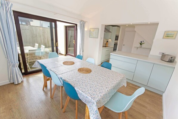 A dining area with a table, chairs, and a view through a glass door to an outdoor space.