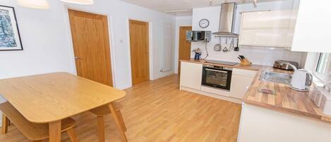 Una cocina moderna con suelo de madera, una mesa de comedor y armarios blancos.