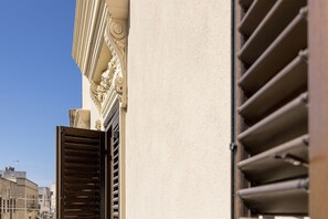 A building facade with ornate architectural details and a partially open window with horizontal blinds. - Dimora La Torre (Favignana)