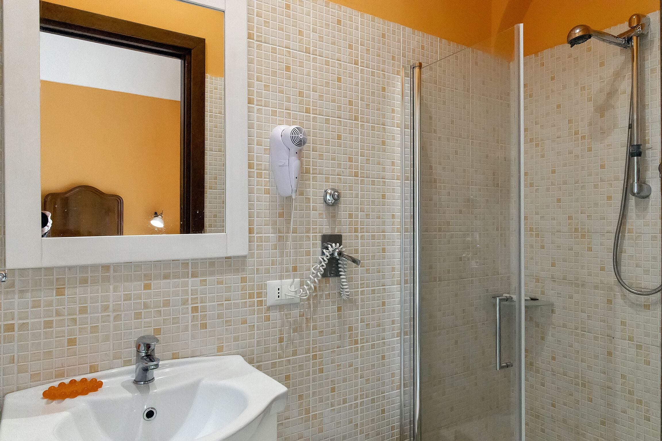 Un baño con lavabo, espejo, secador de pelo y ducha.