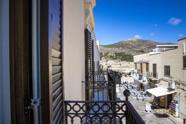 A narrow street with buildings on either side, a mountain in the background, and a clear blue sky. - Dimora La Torre (Favignana)