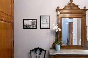 A room with a wooden door, a framed black and white photograph, a framed picture, a potted orchid, and a mirror with a wooden frame. - Dimora La Torre (Favignana)