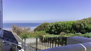 Un balcon avec vue sur l’océan et bordé d’une haie.