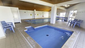 Une piscine intérieure dotée de plusieurs couloirs, de panneaux de signalisation de sécurité et d’espaces pour s’asseoir.