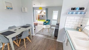 A modern kitchen with a sink, countertop, and a dining area with a table and chairs.