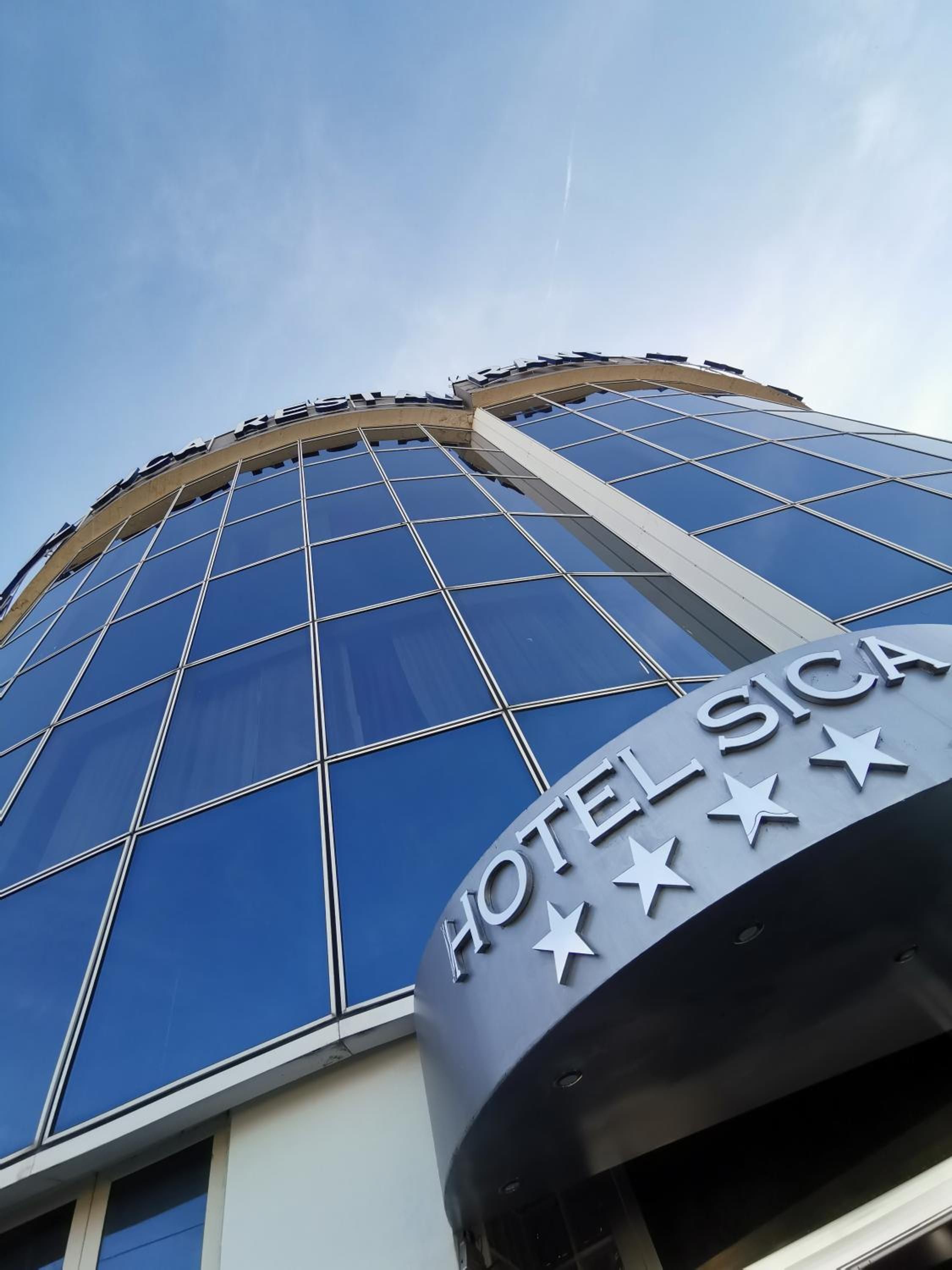 Un moderno edificio de hotel con fachada de vidrio y un letrero llamativo que dice 'HOTEL SICA'.