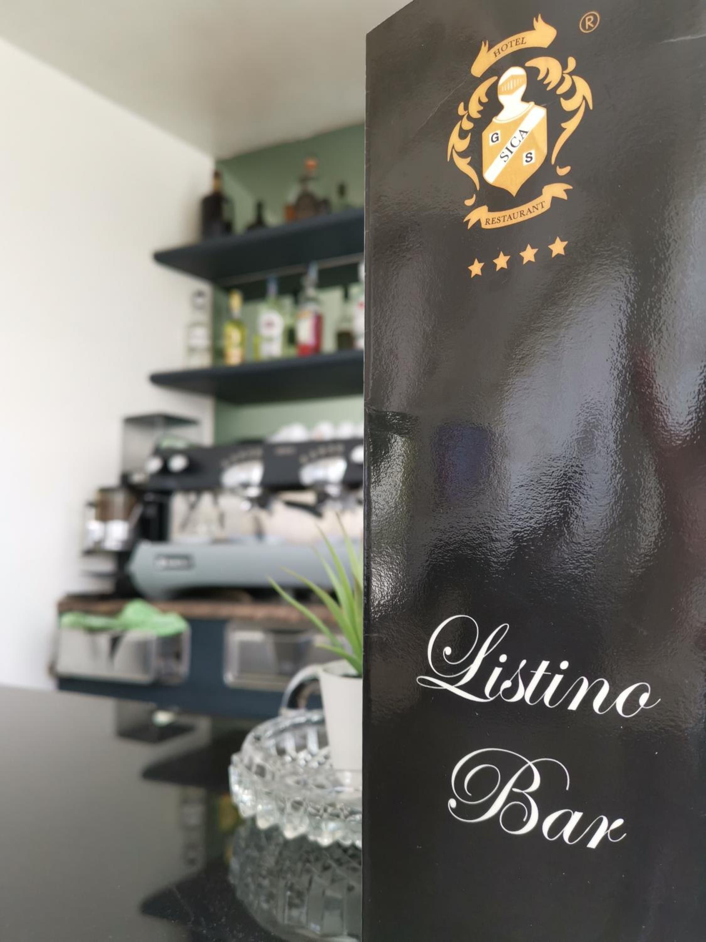 A black glass panel with the text 'Listino Bar' and a crest with 'Hotel Sica Restaurant' on it.