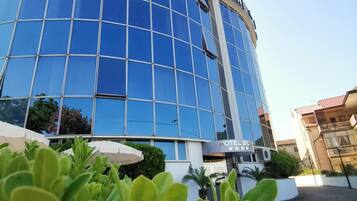 Un moderno edificio de hotel con fachada de vidrio reflectante y un letrero que dice 'HOTEL SICAR RESTAURANT'.