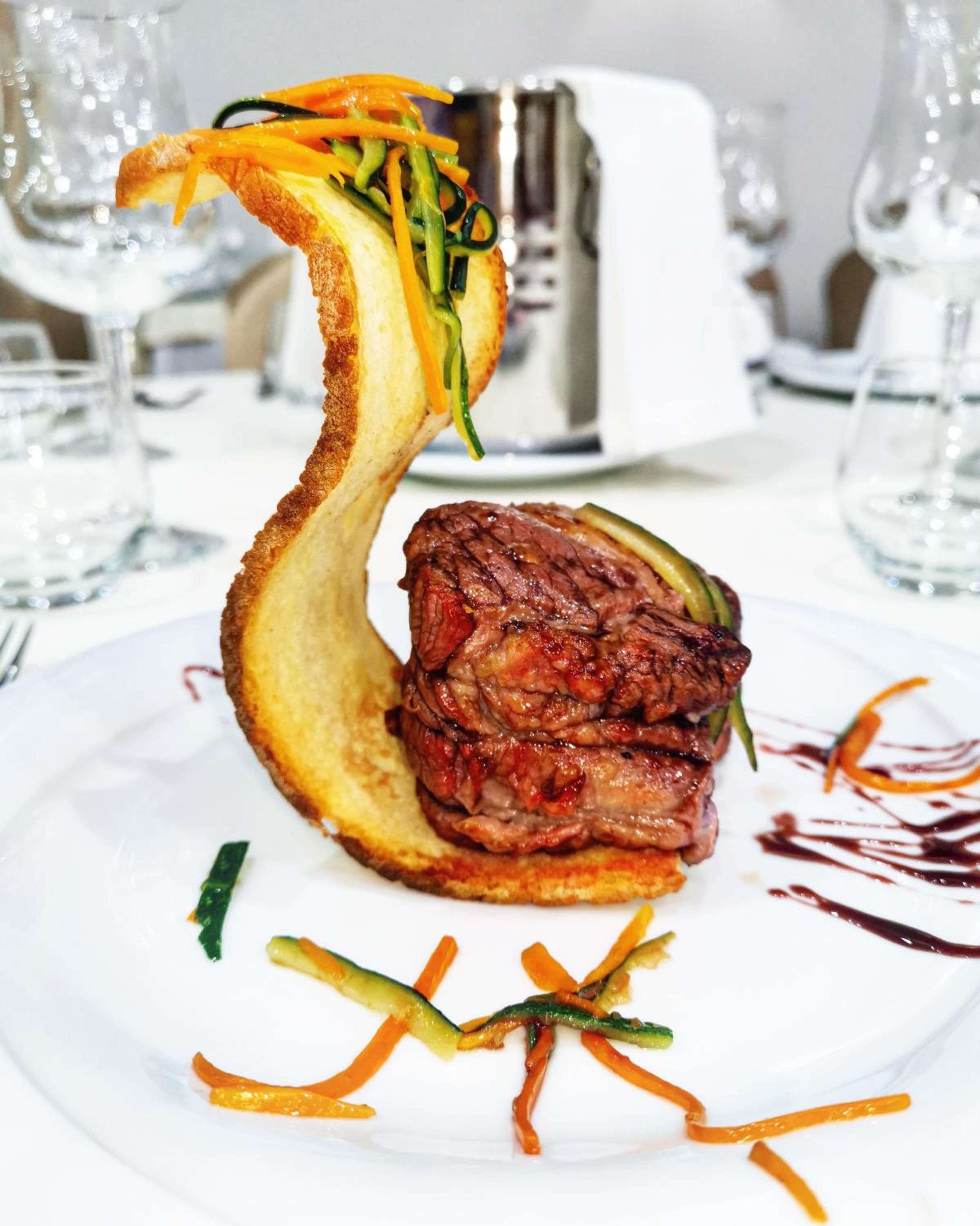 A plated dish with a steak and vegetables.