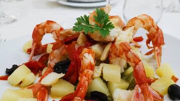 Un plato de mariscos con camarones, papas y aceitunas.