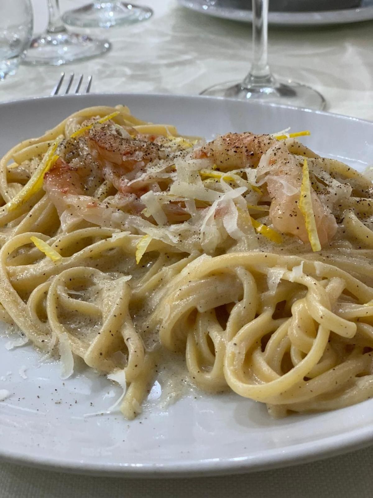 Une assiette de pâtes, agrémentée de zeste de citron et de poivre noir.