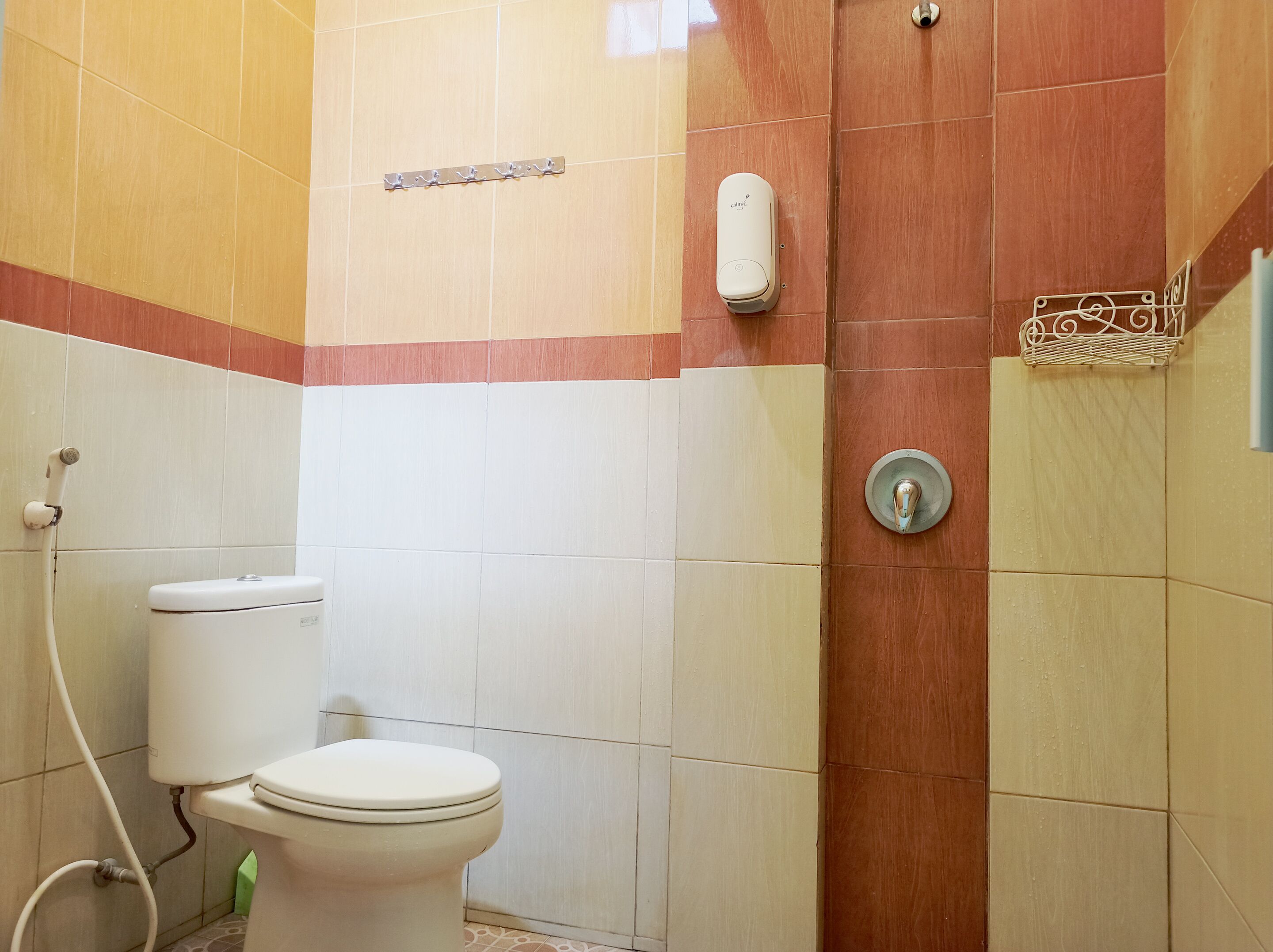 Un baño con inodoro, secamanos y toallero.