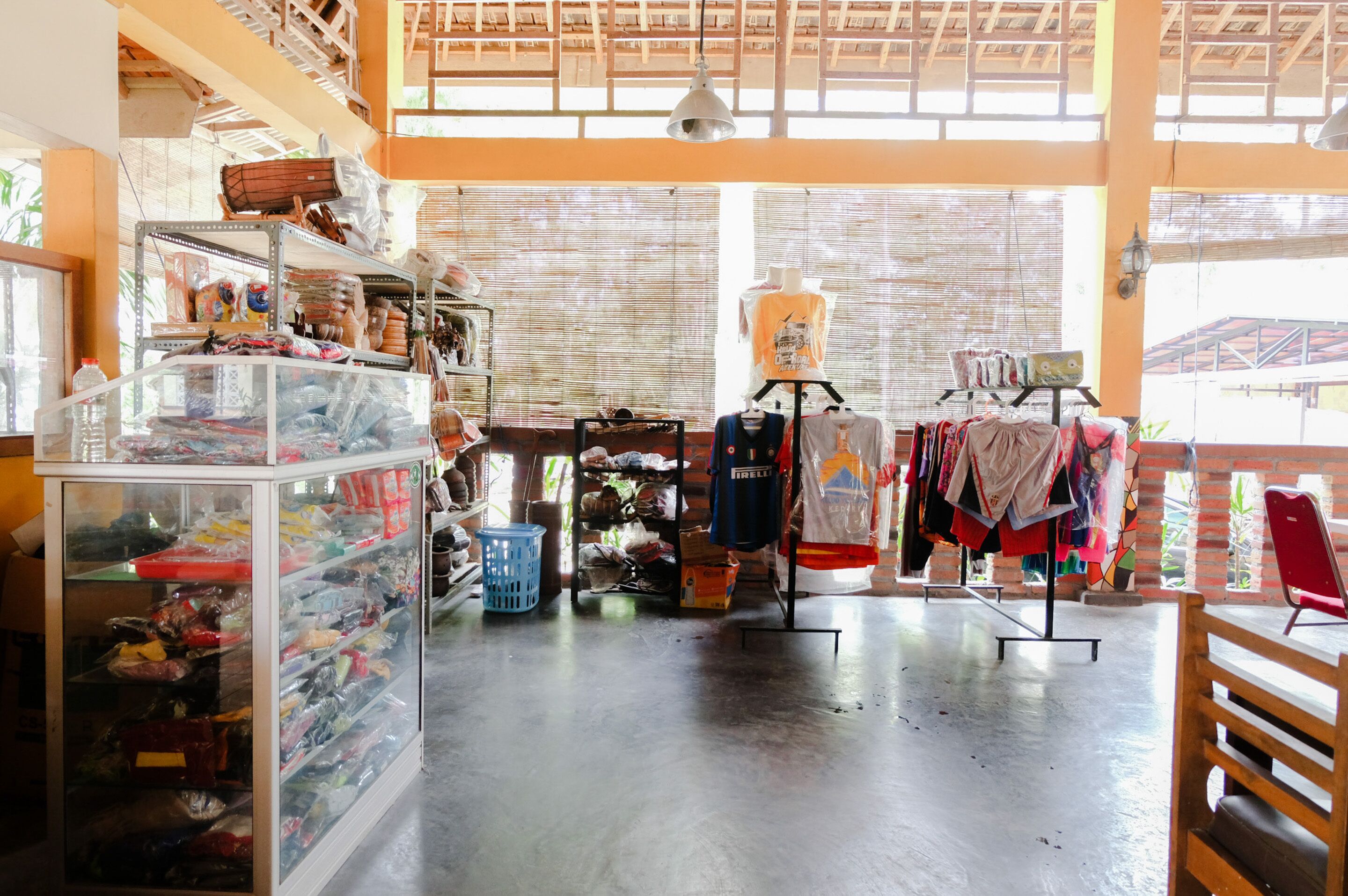 A spacious room with high ceilings and large windows, shelves stocked with various items, and a mannequin displaying clothing.