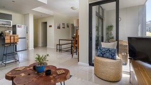 A modern apartment with a kitchen, dining area, and a balcony with a TV. - Flatrock 608 (Cape Town)