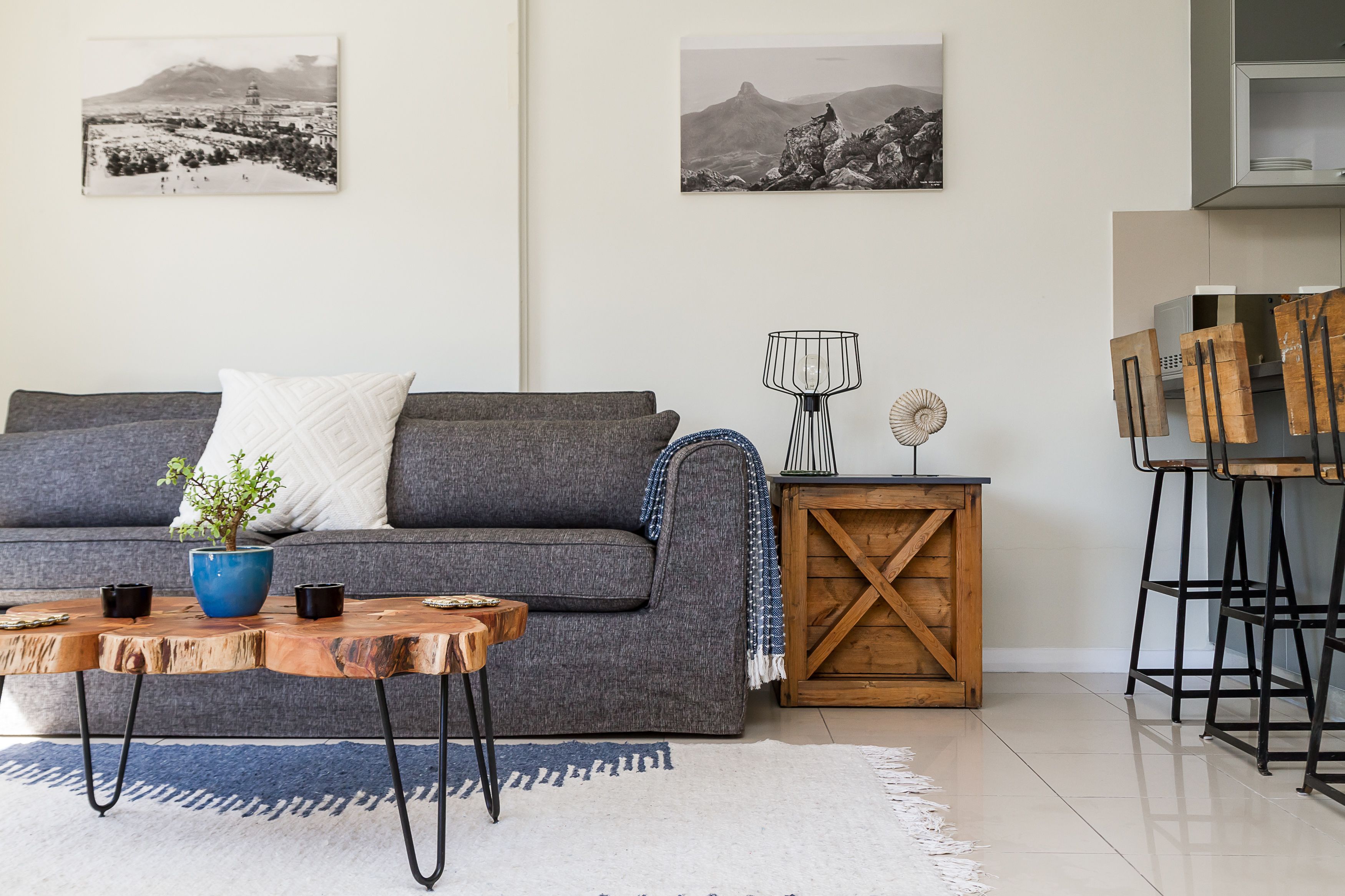 A modern living room with a grey sofa, a wooden coffee table, and a blue vase. There are two black and white photographs on the wall.