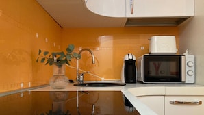 A modern kitchen with a white countertop, a coffee maker, a microwave, and a plant. - Fiuggi Apartment (Milan)