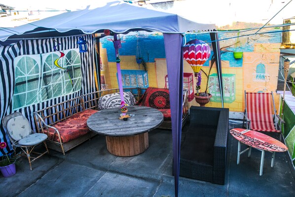 A covered outdoor seating area with a round table, cushioned seating, and a variety of chairs. - Five Trees B&B (Sliema)