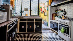 A kitchen with a checkered floor, a stove, an oven, and a refrigerator. - Five Trees B&B (Sliema)