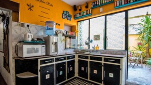 A kitchen with a checkered floor, black cabinets, and a yellow wall with kitchen utensils. - Five Trees B&B (Sliema)