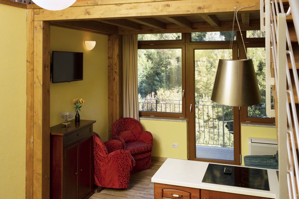 Een compacte keuken met een houten aanrechtblad, een inbouwfornuis en een eethoek met tafel en stoelen.