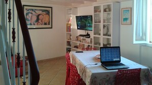 A room with a bed, a laptop on a table, a TV, and a bookshelf. - Sansone apartment (Portoferraio)