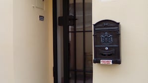 A building entrance with a black gate, a mailbox, and a small sign above the mailbox. - Sansone apartment (Portoferraio)