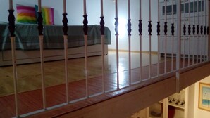 A staircase with wooden balusters leading to a bedroom with a bed, a colorful pillow, and a window. - Sansone apartment (Portoferraio)