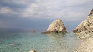 A coastal scene with clear turquoise waters, rocky formations, and a boat in the distance. - Sansone apartment (Portoferraio)