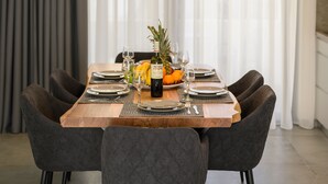 A dining area with a wooden table set for four, surrounded by upholstered chairs. - Athina Suites Platanias (Platanias)