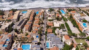 A coastal resort with multiple buildings, swimming pools, and a beach. - Athina Suites Platanias (Platanias)