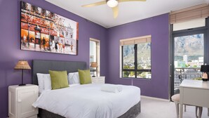 A bedroom with a bed, a desk, and a window with a city view. - Flatrock 703 (Cape Town)