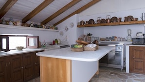 A kitchen with wooden beams, a central island, and various kitchen appliances.