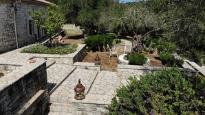 A stone courtyard with a lantern, potted plants, and a rustic building.