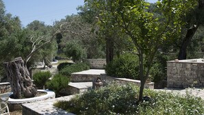 A landscaped garden with stone walls, a large tree, and a variety of shrubs and flowers.