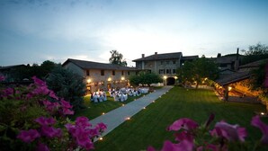 A wedding reception at a historic stone building with a paved pathway leading to a seated area. - Il Vagabondo (Buttrio)