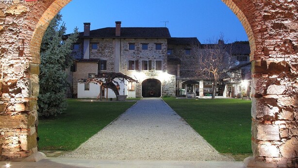 A stone archway leading to a building with a paved pathway. - Il Vagabondo (Buttrio)