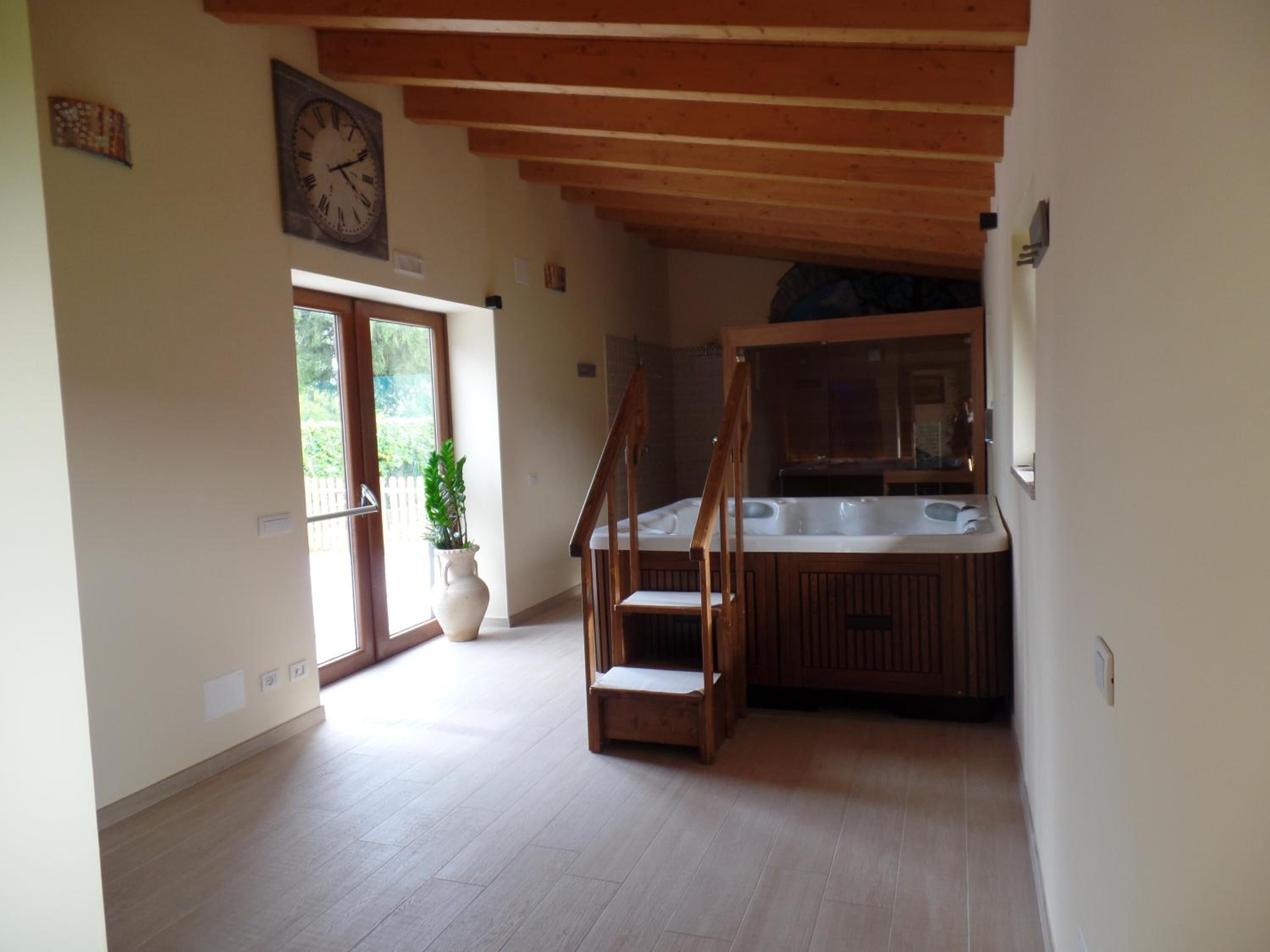 Une pièce spacieuse avec un escalier en bois, une grande fenêtre et un jacuzzi intégré.