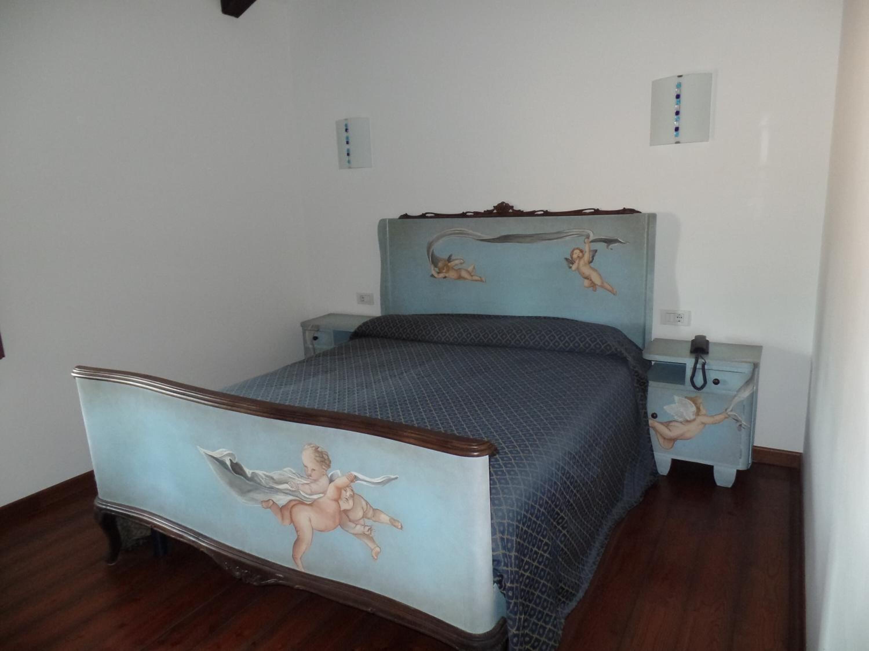 A bedroom with a bed, two bedside tables, and a wall with a mural.
